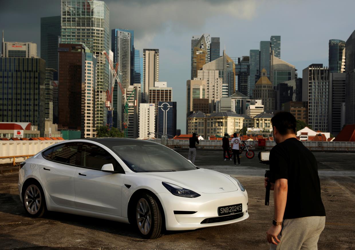 Tesla car owner Tim Shim, 42, films an “unboxing” video of his new Model 3 car in Singapore October 25, 2021. REUTERS/Edgar Su