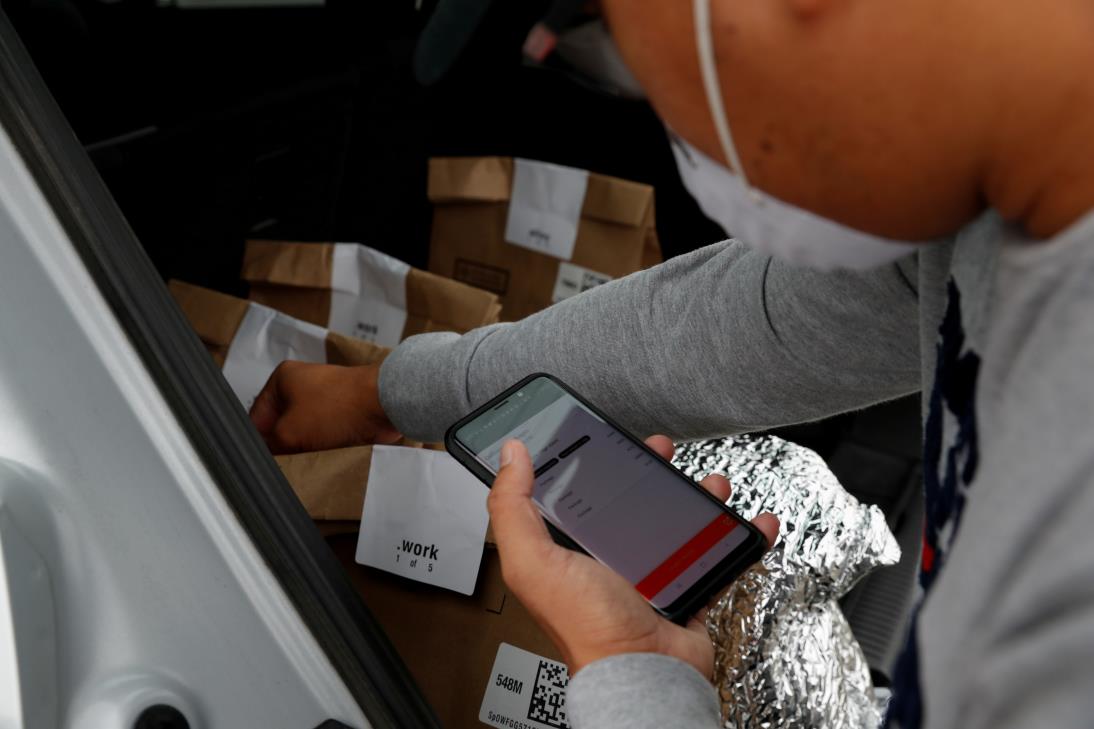 An independent co<em></em>ntract delivery driver for Amazon Flex, holds his iPhone with the Amazon Flex app showing his deliveries near a Whole Foods Market, as spread of the coro<em></em>navirus disease (COVID-19) continues, in Dublin, California, U.S., April 6, 2020. REUTERS/Shannon Stapleton/File Photo