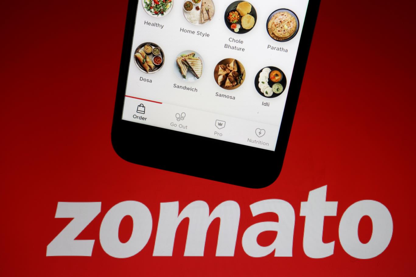 The app of Indian food delivery company Zomato is seen on a mobile phone above its logo displayed in this illustration picture taken July 14, 2021. REUTERS/Florence Lo/Illustration/File Photo