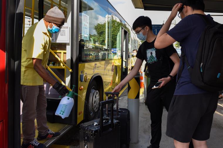 A bus driver sprays disinfectant on the luggage of passengers travelling to Malaysia as the Vaccinated Travel Lane between Singapore and Malaysia opens after the land border between the two countries reopened following nearly two years of being shut down due to the coro<em></em>navirus disease (COVID-19) pandemic, at a bus station in Singapore November 29, 2021. REUTERS/Caroline Chia