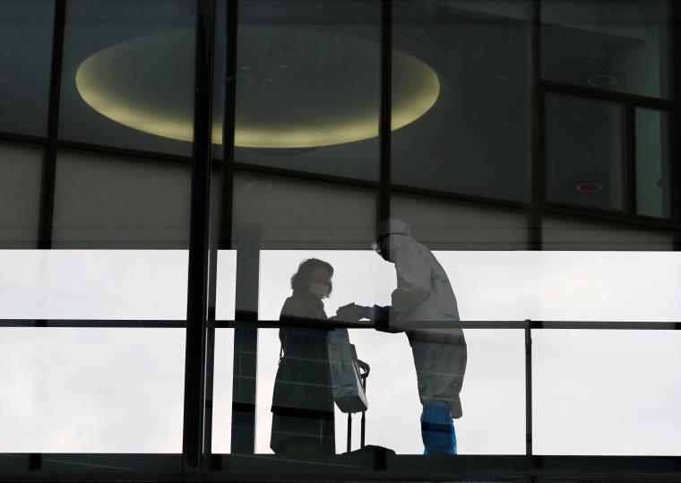 A staff wearing a protective suit checks temperature of a passenger boarding an internatio<em></em>nal flight at Narita internatio<em></em>nal airport on the first day of closed borders to prevent the spread of the new coro<em></em>navirus Omicron variant amid the coro<em></em>navirus disease (COVID-19) pandemic, in Narita, east of Tokyo, Japan, November 30, 2021. REUTERS/Kim Kyung-Hoon