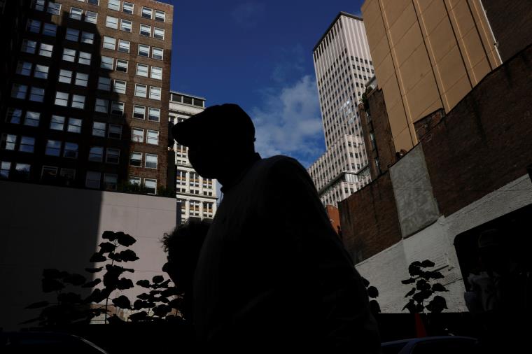 A man is seen silhouetted wearing a protective face mask, amid the coro<em></em>navirus disease (COVID-19) pandemic, walking near the financial district of New York City, U.S., October 18, 2021. REUTERS/Shannon Stapleton