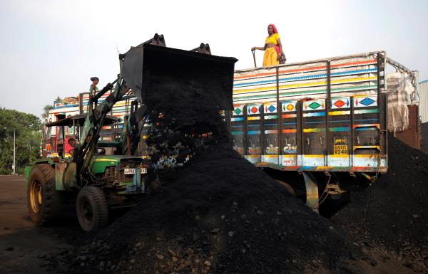 Workers unload coal from a supply truck at a yard on the outskirts of Ahmedabad