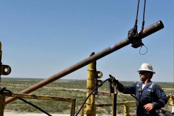 A drilling crew member raises drill pipe o<em></em>nto the drilling rig floor on an oil rig in the Permian Basin near Wink