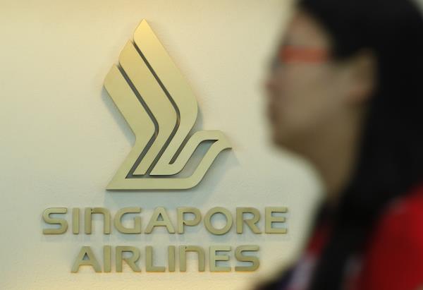 A woman walks past a SIA logo at a ticketing booth at Changi airport in Singapore