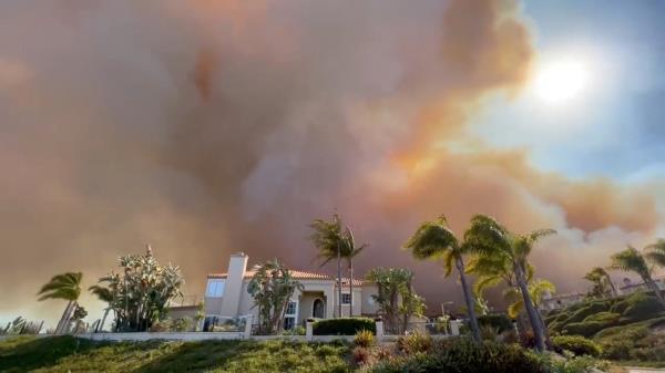 Smoke from a wildfire rises above a residential area in Laguna Niguel