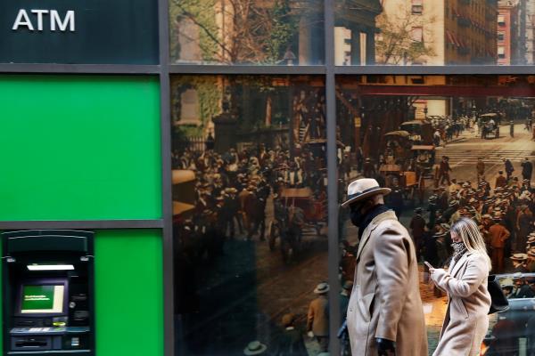 People wearing protective face masks walk, as the global outbreak of the coro<em></em>navirus disease (COVID-19) continues, in the financial district of New York