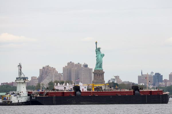 A tug boat pushes an oil barge through New York Harbor