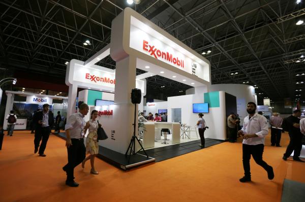 FILE PHOTO - People walk near the booth of the Exxon Mobil Corp at the Rio Oil and Gas Expo and Co<em></em>nference in Rio de Janeiro