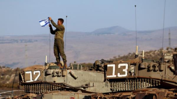 A soldier installs an Israeli flag on a tank during a military drill near Israel&#039;s border with Lebanon in northern Israel, October 26, 2023. REUTERS/Lisi Niesner/File Photo