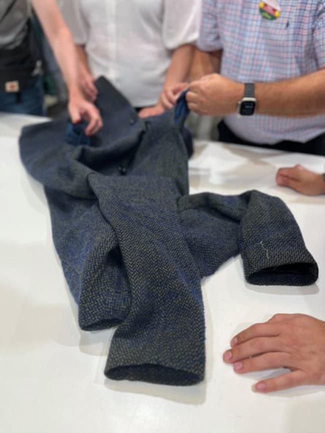 Workers examine a jacket on a white table