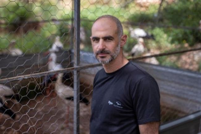 Michael Sawan stands next to an enclosure for birds