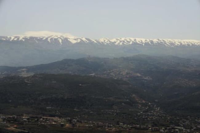 A snow-capped mountain range next to an urban valley