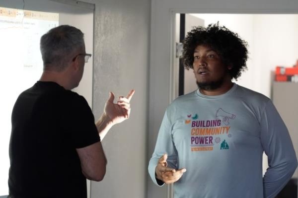 Randy Parraz, left, co-founder and president of the Organizing Institute for Democracy, helps in a role playing lecture at a Poder In Action voter canvassing event