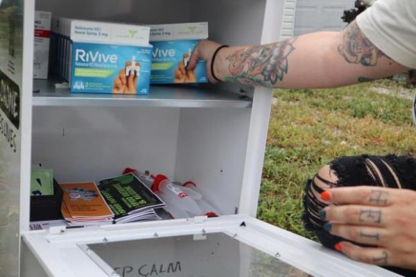 Tasha Withrow, a person in recovery and co-founder of harm reduction organization Project Mayday, refills a new naloxone distribution box in a residental neighborhood of Hurricane, W.Va. on Tuesday, Sept. 24, 2024. (AP Photo/Leah Willingham)