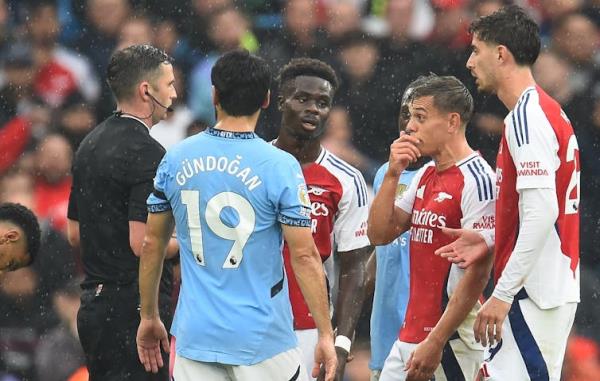 Referee Michael Oliver (L) shows a red card to Arsenal's Leandro Trossard (2-R) during the English Premier League match between Manchester City and Arsenal.