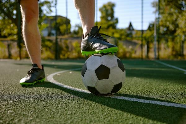 Close-up of a man's foot on top of a football on a sunny day