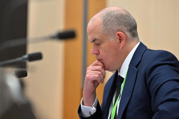 A man in a suit holds his chin in thought.