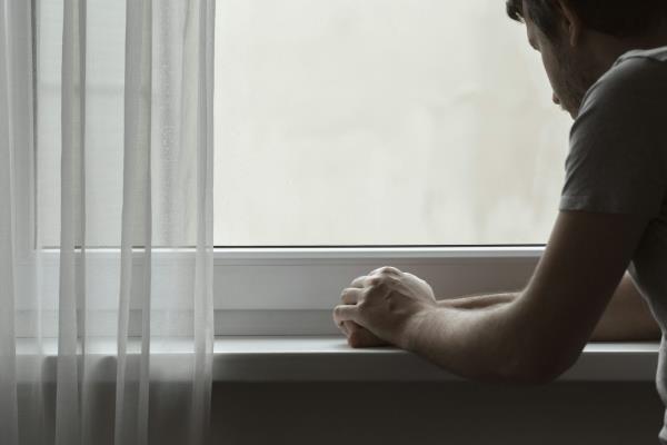 A young man stares out a window