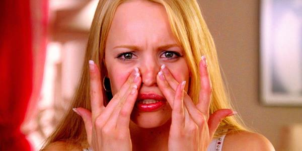 Rachel McAdams as Regina George touching her face while looking in a mirror in Mean Girls 2004