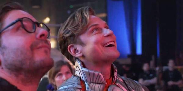 Billy Magnussen as Adam and Daniel Brühl as Eric looking up at something and smiling in The Franchise.