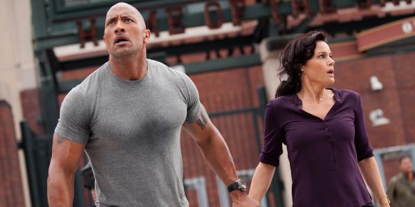 Dwayne Johnson as Ray and Carla Gugino as Emma looking worried and holding hands in San Andreas