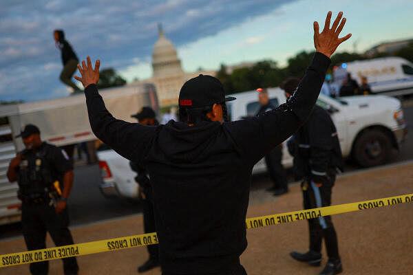 A demo<em></em>nstrator raises their arms as police officers stand guard during a protest in support of Native American tribes in front of the U.S. Capitol, in Washington.