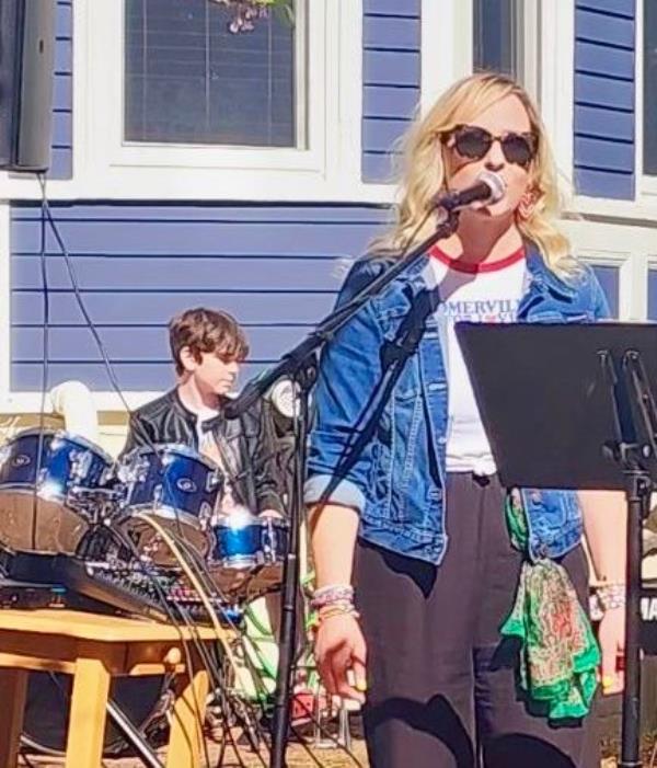 The author sings at an event with her son, Heath, drumming in the background.