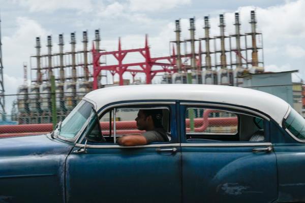 A person drives a classic American car past a floating generator that has not been producing electricity for days in Havana, Cuba, Friday, Oct. 18, 2024. (AP Photo/Ramon Espinosa)