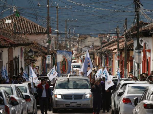 People walk next to a hearse carrying the coffin with the body of priest Marcelo Perez, through the streets in San Cristobal de las Casas, wher<em></em>e he was killed on Sunday after officiating a mass, in San Cristobal de las Casas, in the southern state of Chiapas, Mexico, October 20, 2024. REUTERS/Gabriela Sanabria