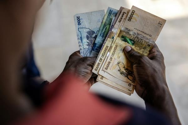 A man displays Ugandan shilling notes.