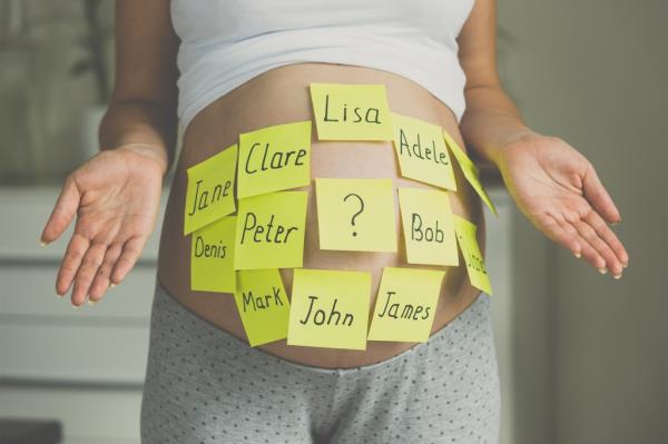 A pregnant woman with post-it notes of baby names on her belly.