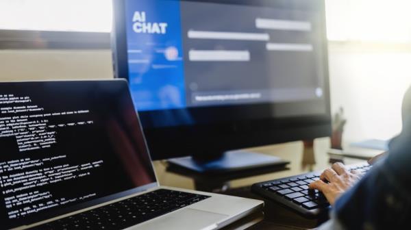 Programmer using generative artificial intelligence for software development, typing on a keyboard in an office setting