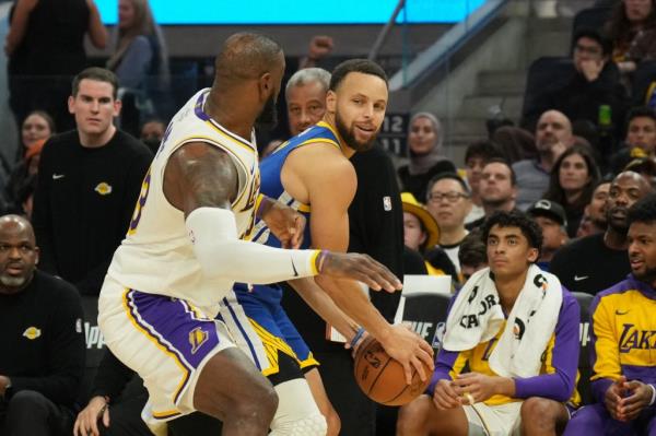 Golden State Warriors guard Stephen Curry (center right) handles the ball against Los Angeles Lakers forward LeBron James (center left) during the fourth quarter of last night's game.