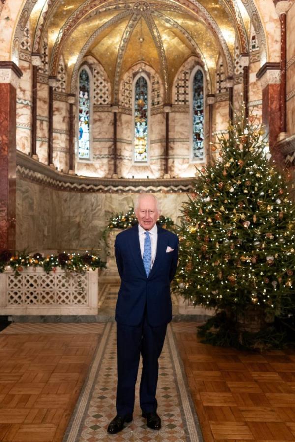 King Charles of Britain standing in front of a Christmas tree, recording his Christmas message at Fitzrovia Chapel, London.