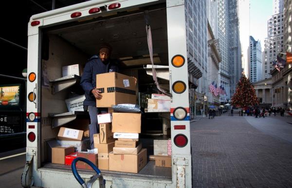 FILE PHOTO: A U.S. Postal Service employee prepares to deliver packages on Christmas Eve at Wall Street in New York, December 24, 2013.  
