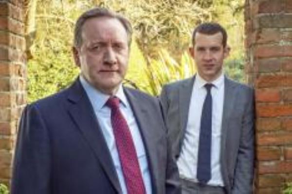 Neil Dudgeon and another man in suits standing in front of trees in a scene from Midsomer Murders