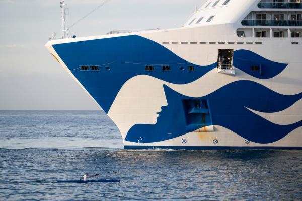 Person in a kayak near the large 'Sky Princess' cruise ship entering Funchal harbour, Madeira, Portugal on 23rd April 2024