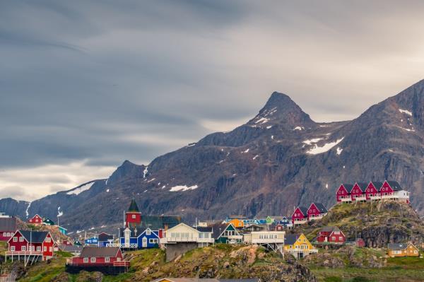 A group of colorful houses on a hill in Sisimiut, an arctic village in Greenland, with a steep mountain ridge in the background