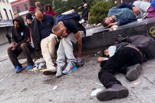 Drug addicts sleeping on the ground and a bench in Roberto Clemente Plaza on Nov. 13, 2024.