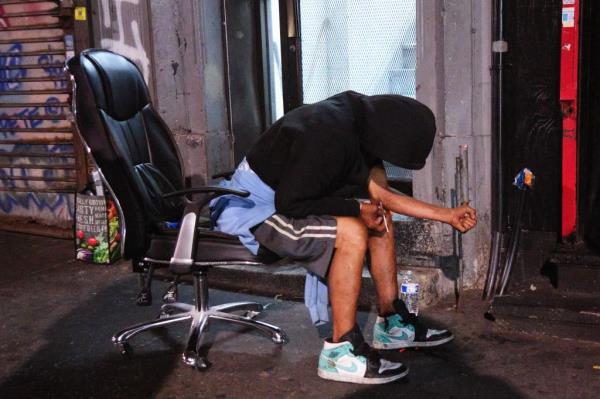 A man using a syringe to inject drugs in his arm outside a business on Melrose Avenue on Aug. 30, 2024.