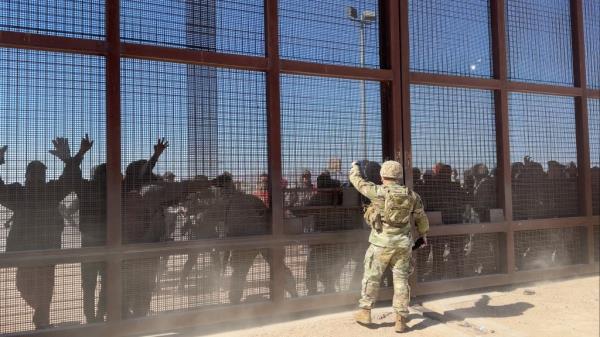 The Post captures hundreds of migrants rushing the border wall as a soldier yells out to step back,