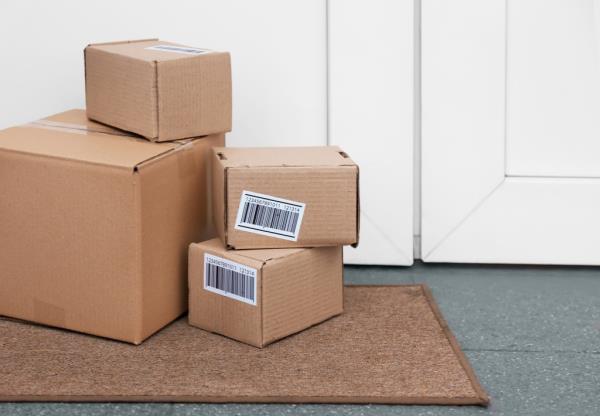 A group of delivered cardboard boxes on a mat near the front door