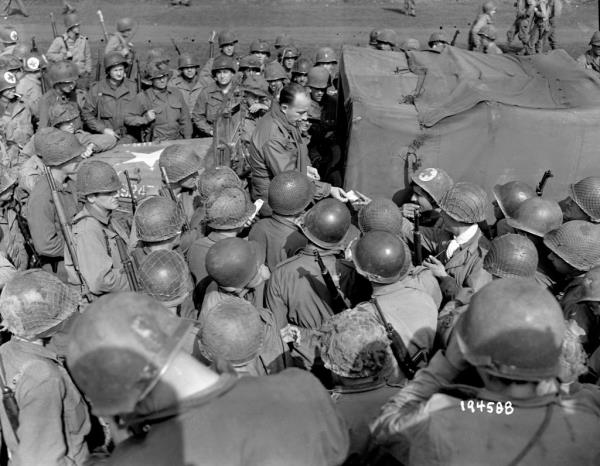 Bing Crosby signs autographs for American infantry troops in France, 1944.