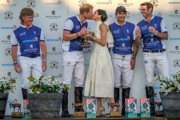 Prince Harry in polo gear being kissed by Meghan Markle.