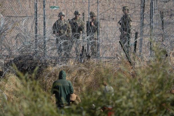 Texas Natio<em></em>nal Guard troops keep an eye on a group of migrants who crossed the Rio Grande attempting to turn themselves into U.S. Border Patrol 