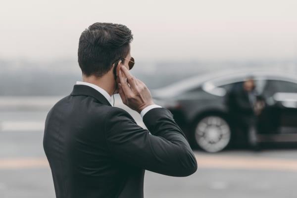 Handsome bodyguard in suit standing and listening to a message via security earpiece on helipad