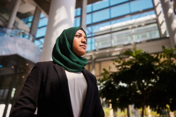 Low angle view of a co<em></em>nfident young muslim businesswoman wearing a hijab standing in the lobby of a modern office building